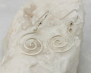 Silver dangle spiral earrings on white rock