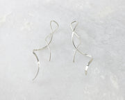 silver spiral threader earrings on white marble