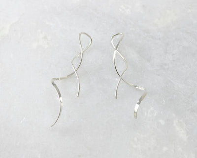 silver spiral threader earrings on white marble
