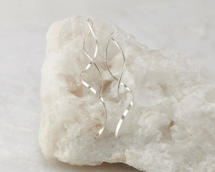 Silver dangle spiral threader earrings on white rock