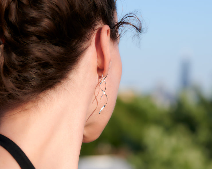 close up of woman wearing silver spiral threader earrings