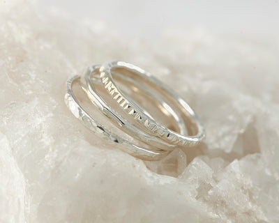 Silver hammered stacking rings on white rock