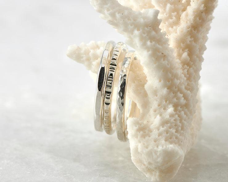 Silver hammered stacking rings on coral