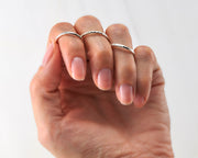 woman wearing 3 silver stacking rings of different finishes