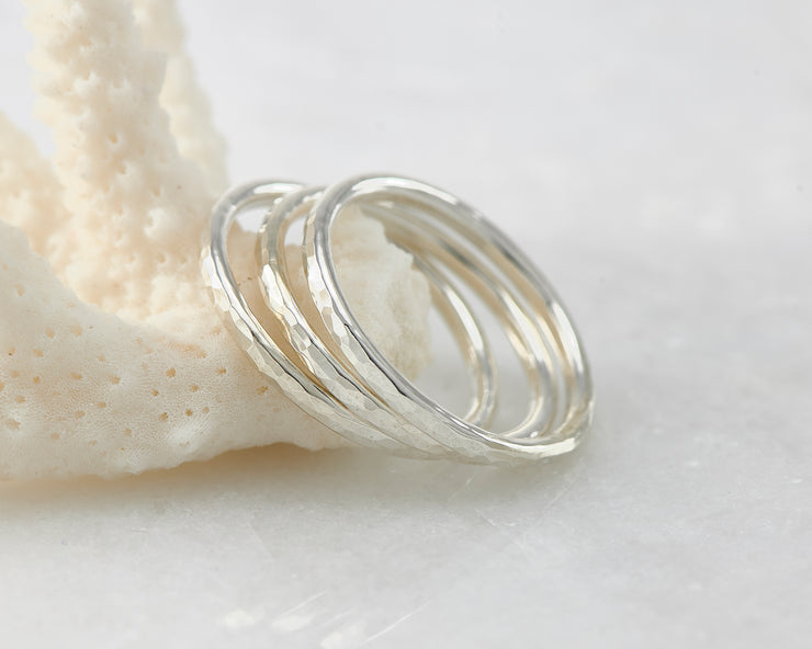 Silver hammered stacking rings on coral