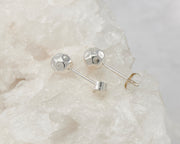 Silver stud ball earrings on white rock