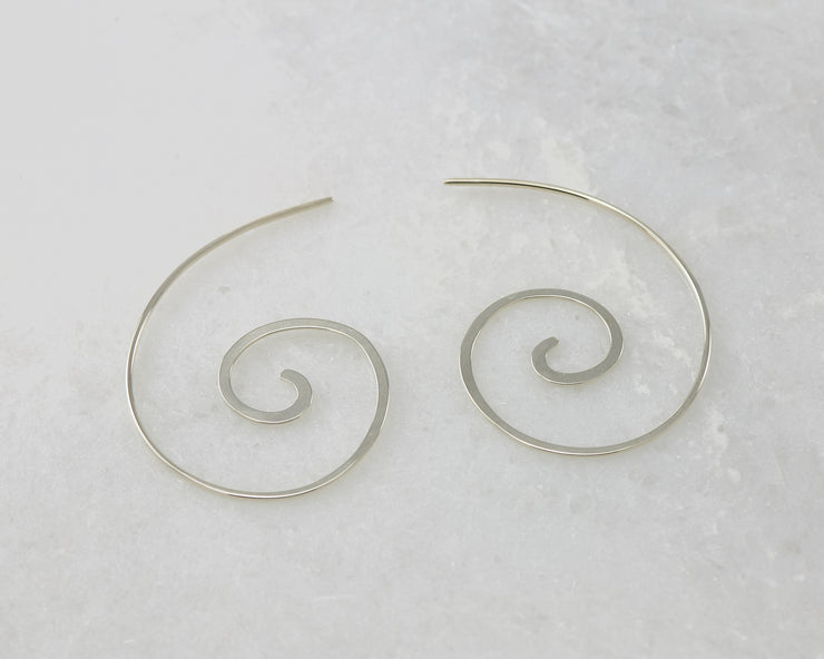 silver swirl threader earrings on white marble