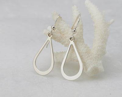 Silver teardrops earrings on coral