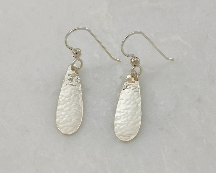 Silver polished teardrops earrings on white marble
