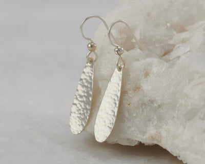 Silver teardrops earrings on white rock