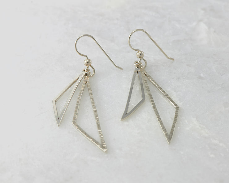 Silver polished triangle earrings on white marble
