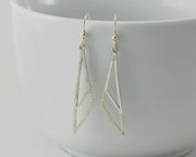 Silver triangle earrings on white cup