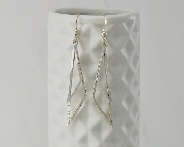 Silver triangle earrings on geometric vase