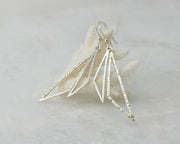 Silver triangle earrings on coral