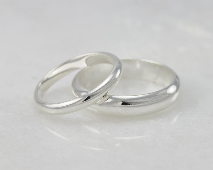 silver wedding band set laying on white marble