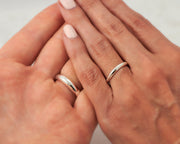 his and hers silver wedding bands on man and woman's hands