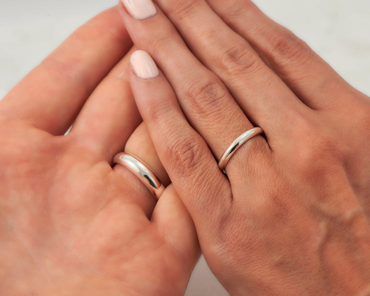 his and hers silver wedding bands on man and woman's hands