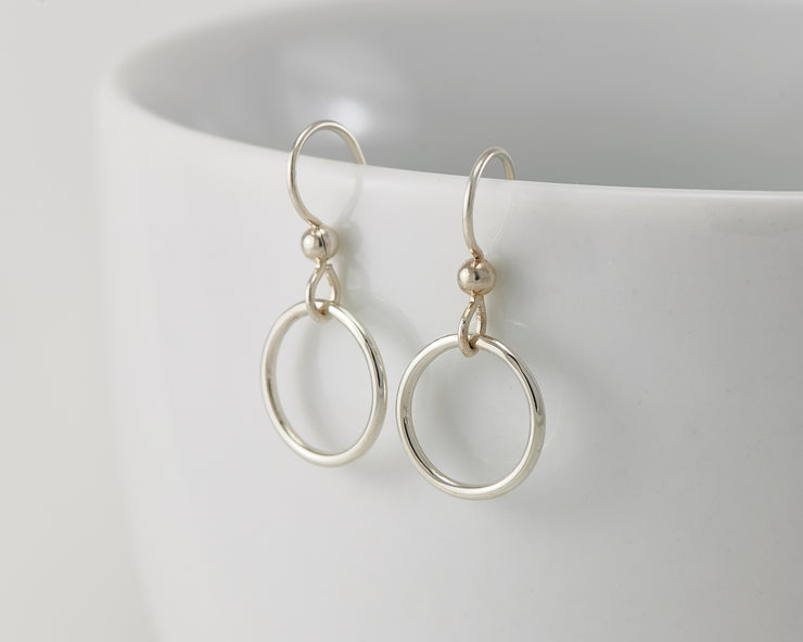 silver small hoop earrings on white cup