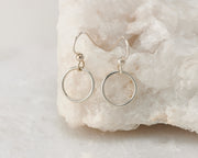 Silver dangle small hoop earrings on white rock