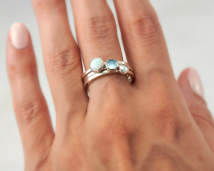 woman wearing opal, pearl, blue topaz silver stacking rings