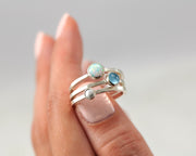 woman balancing silver stacking rings opal, pearl, blue topaz