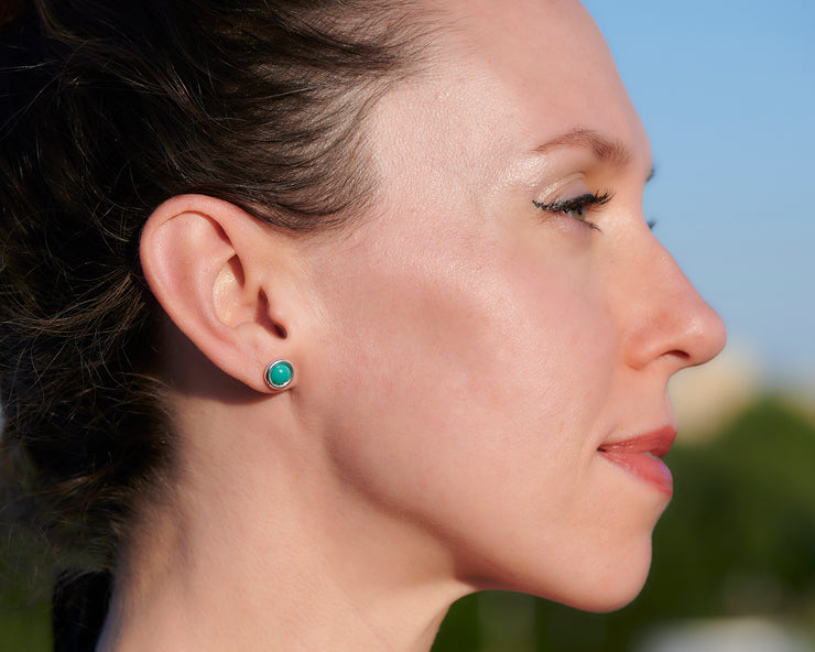 close up of woman wearing silver turquoise stud earrings