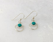 Silver polished turquoise hoop earrings on white marble