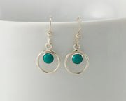Silver turquoise hoop earrings on white cup