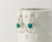 Silver polished turquoise hoop earrings on dotted vase