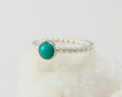 Silver turquoise beaded ring on white rock