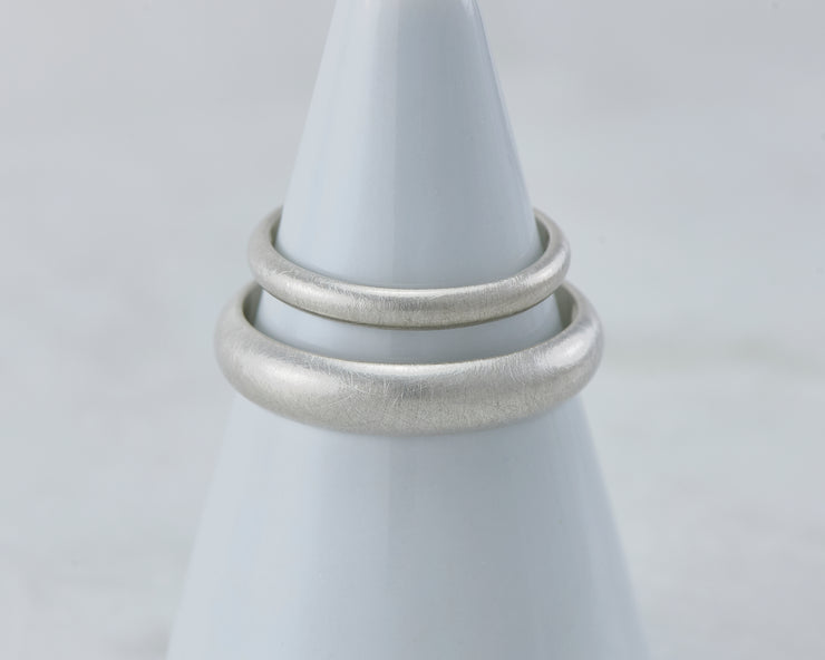 two brushed wedding bands on white ring holder