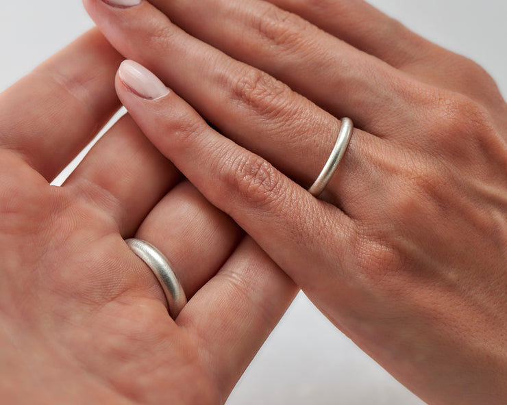 Man and woman holding hands wearing brushed wedding bands
