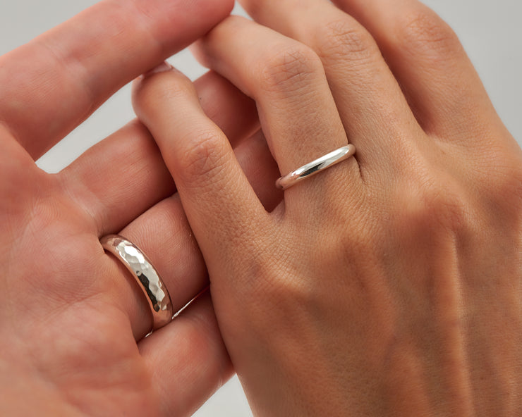 Man and woman holding hands wearing wedding bands